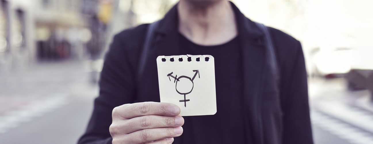 A person holds up a piece of paper with combined gender symbols.
