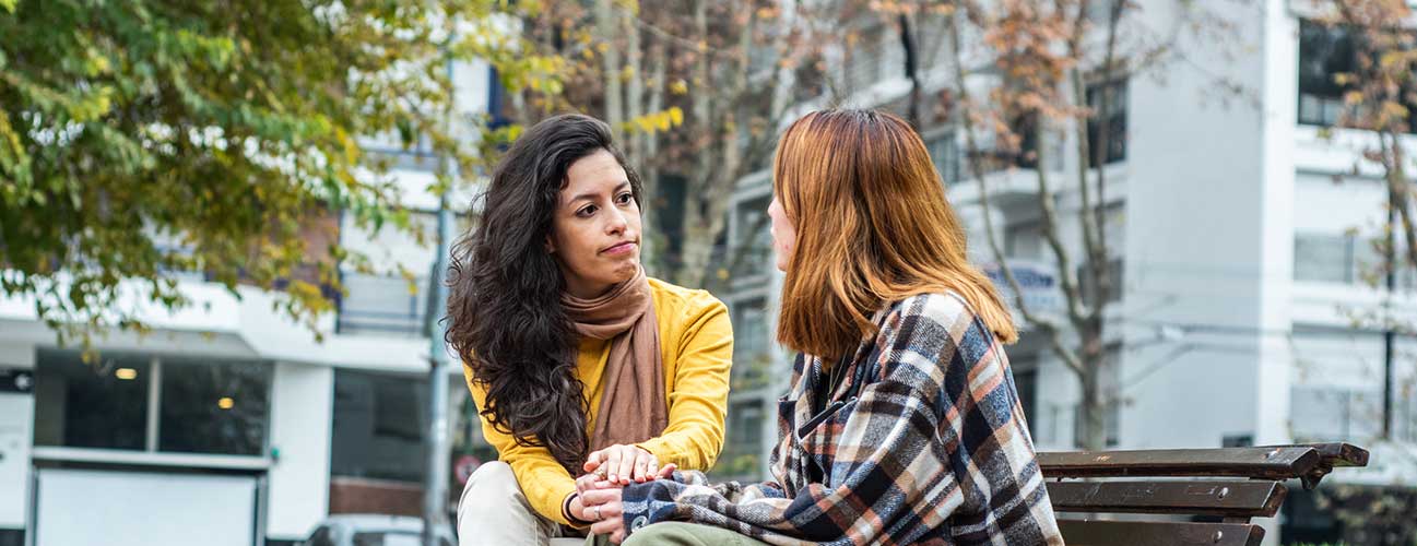 Two friends having a heart to heart conversation on a park bench
