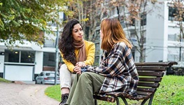 Two friends having a heart to heart conversation on a park bench