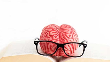 brain with glasses and book