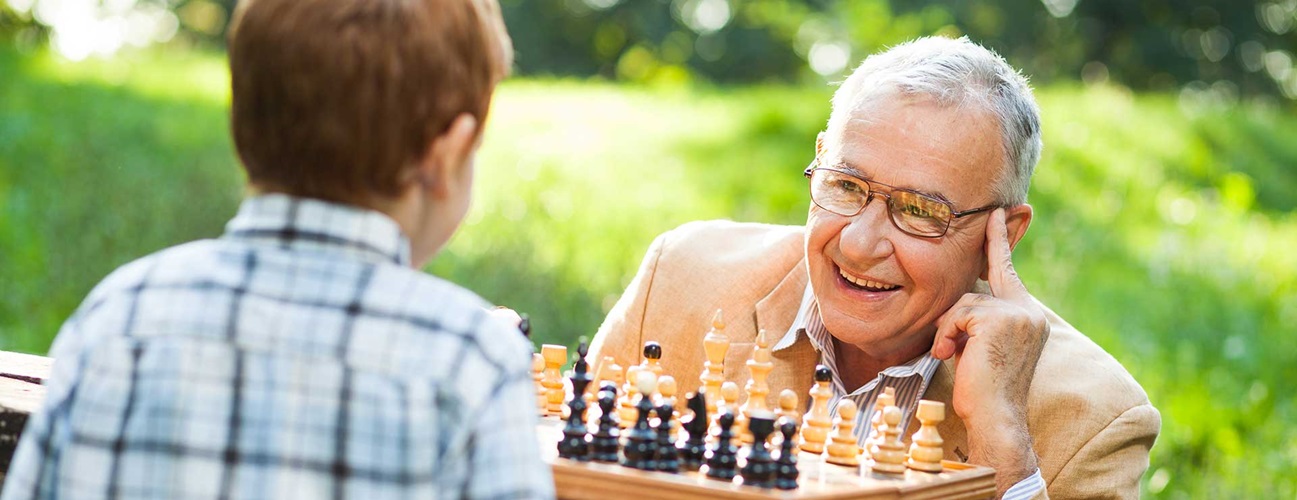senior man plays chess with child
