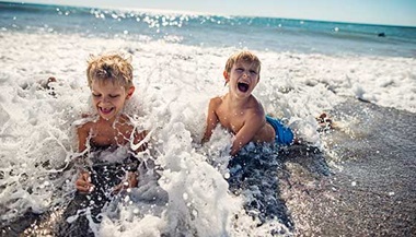 Two young boys play in the ocean waves.