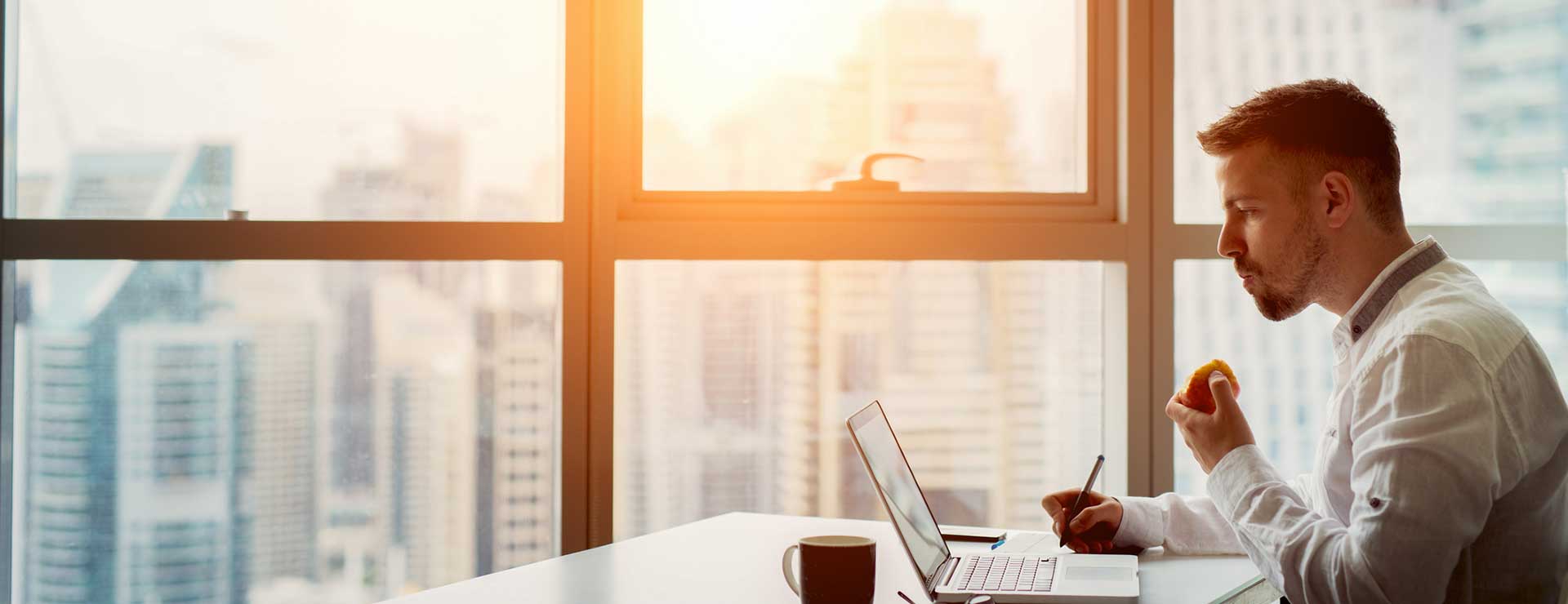 Man works on laptop in front of city skyline