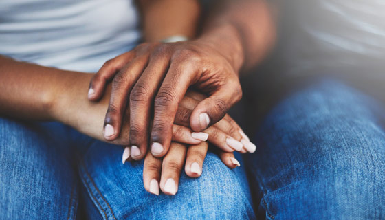 A couple comfortingly holding hands