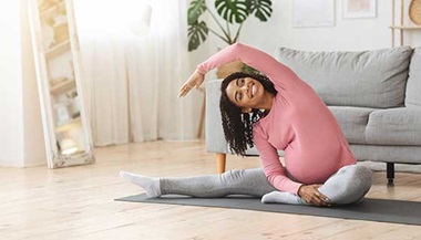 Pregnant woman doing yoga in her house.
