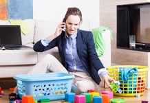 woman in work clothes surrounded by laundry basket and children's toys