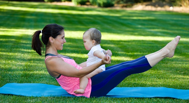 New mother doing yoga with baby in park