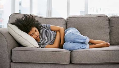 Woman laying on the couch with stomach cramps