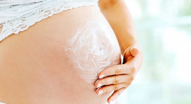 Pregnant woman rubbing creams on belly