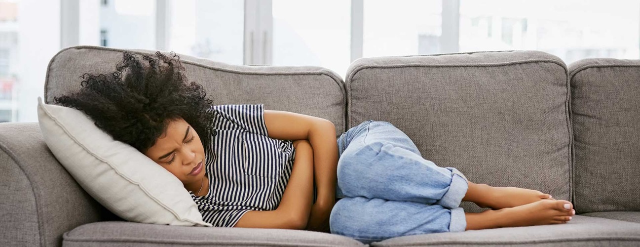 woman laying on a couch with period cramps