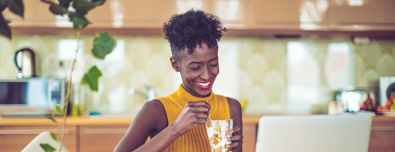 A woman smiles eating yogurt at home