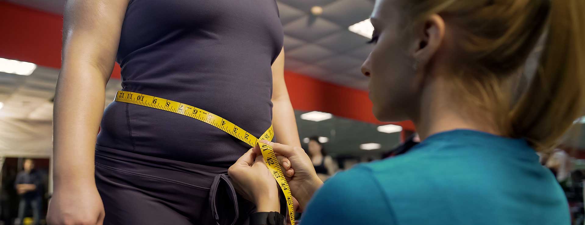 A trainer measuring the waist of a woman