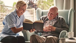 A caregiver reads to a senior man.