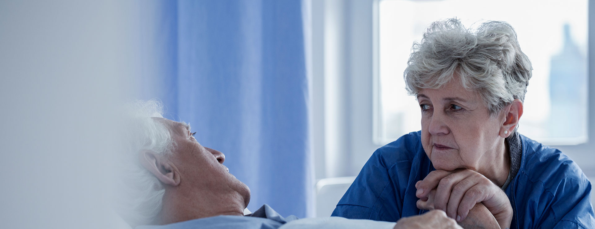 woman holding a man's hand who is laying in bed
