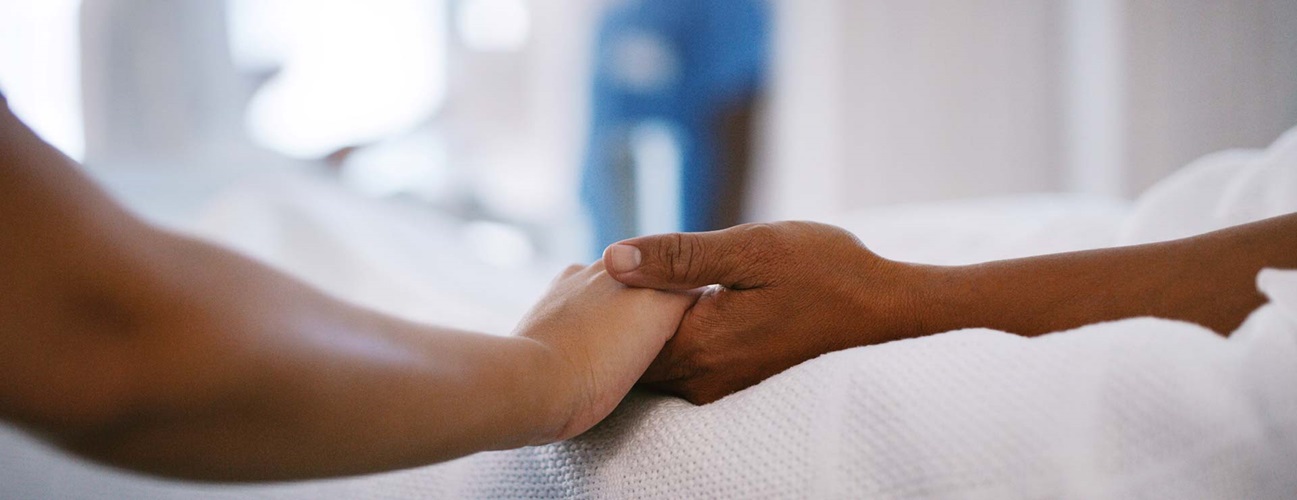 Holding a loved one's hand in a hospital room