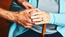 Person providing help and elder care to woman with a cane