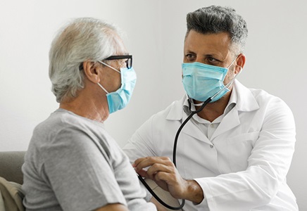Doctor taking elderly patient's heartbeat