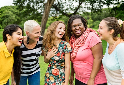 A diverse group of women laugh with each other outdoors