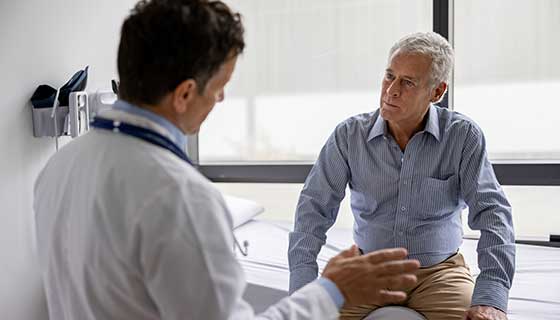 Doctor speaks to adult male patient in an exam room