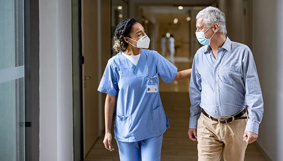 Friendly doctor walking with patient along a hallway