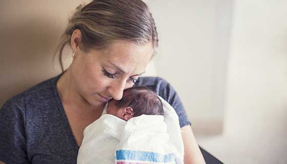 Mom embracing newborn baby