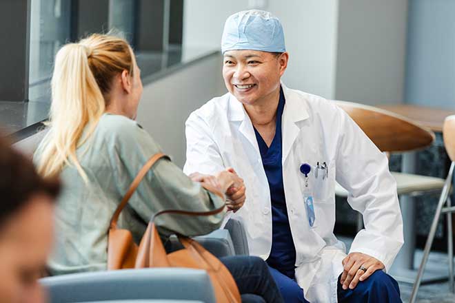 Surgeon shakes a caregiver's hand in the waiting area