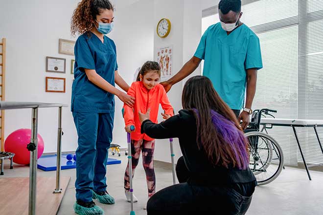Doctor and therapists help a young girl walk