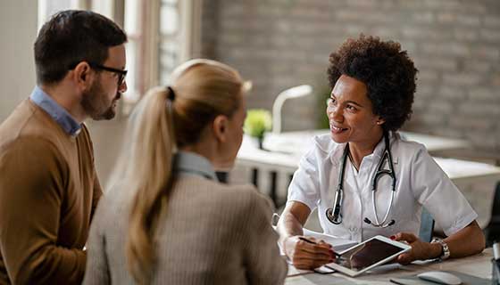 Doctor discusses care with couple holding hands