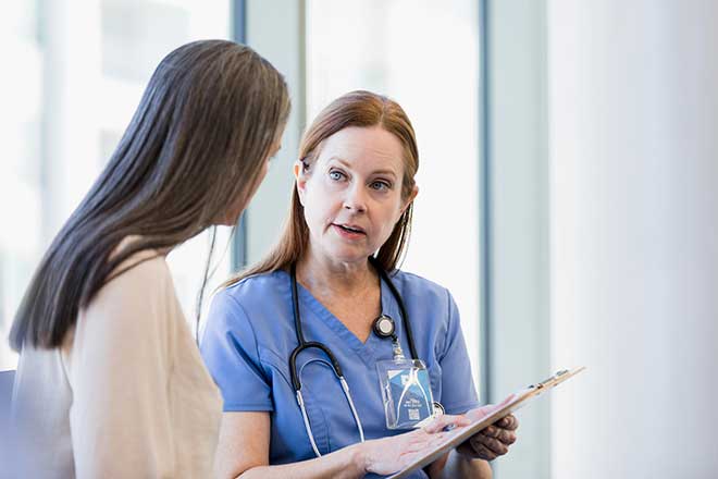 Surgeon speaking with her patient in a bright room
