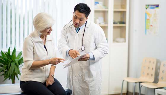 Surgeon speaking with seated patient in an exam room