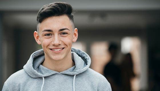 Smiling teenager wearing a gray sweatshirt