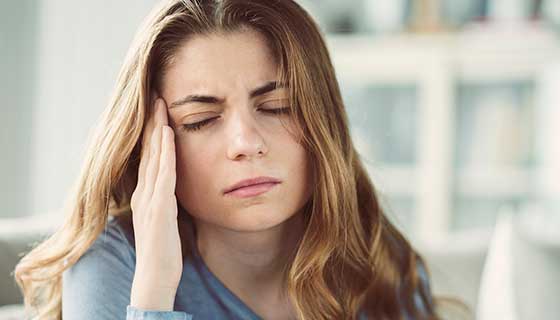 Woman rubs the side of her face in pain
