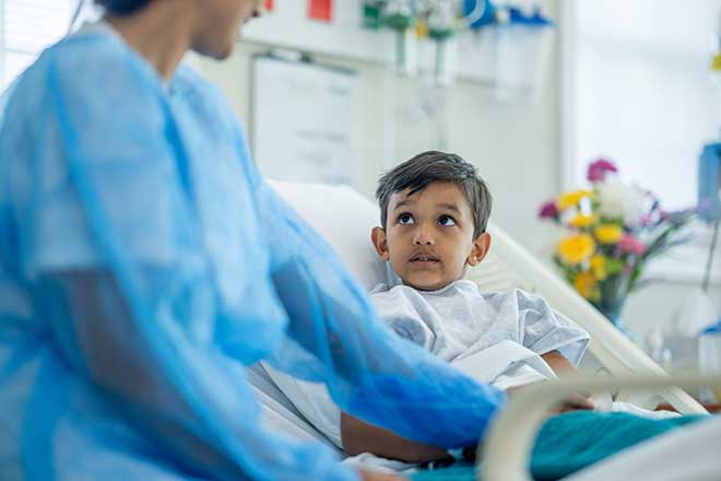 Kind surgeon speaks with young boy on a hospital bed