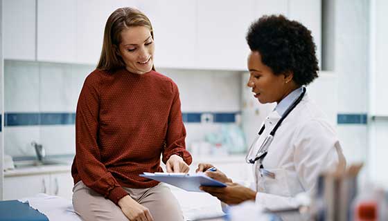 Gynecologist speaks to a young woman in an exam room