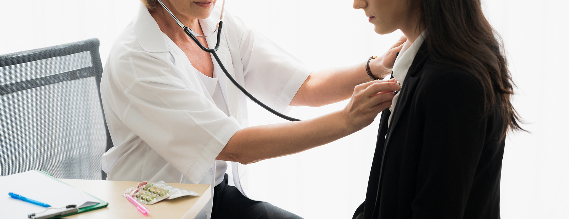 doctor listening to woman's chest