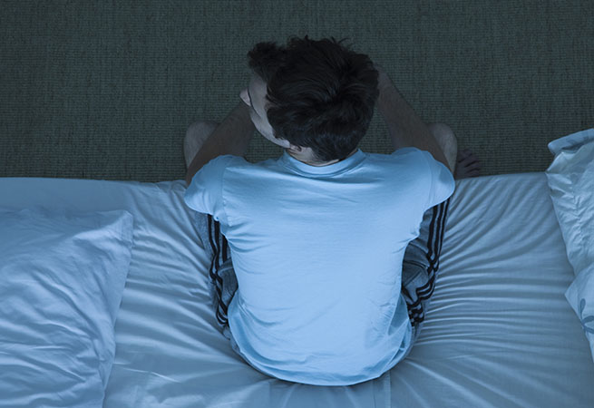 Man sitting up in bed, unable to sleep