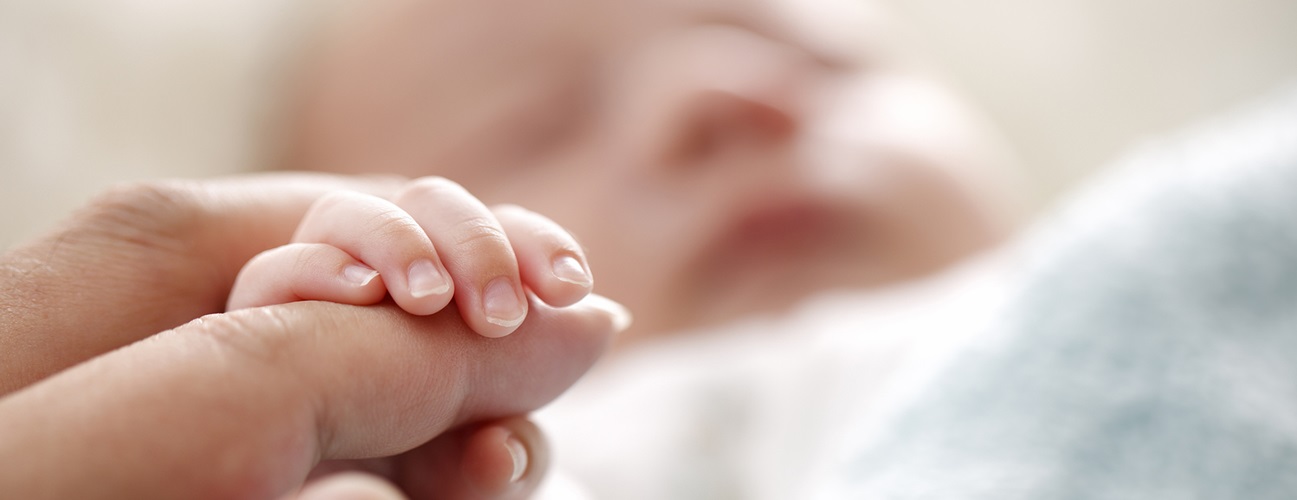 newborn holding woman's finger
