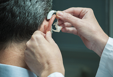 doctor placing hearing aid to a patient