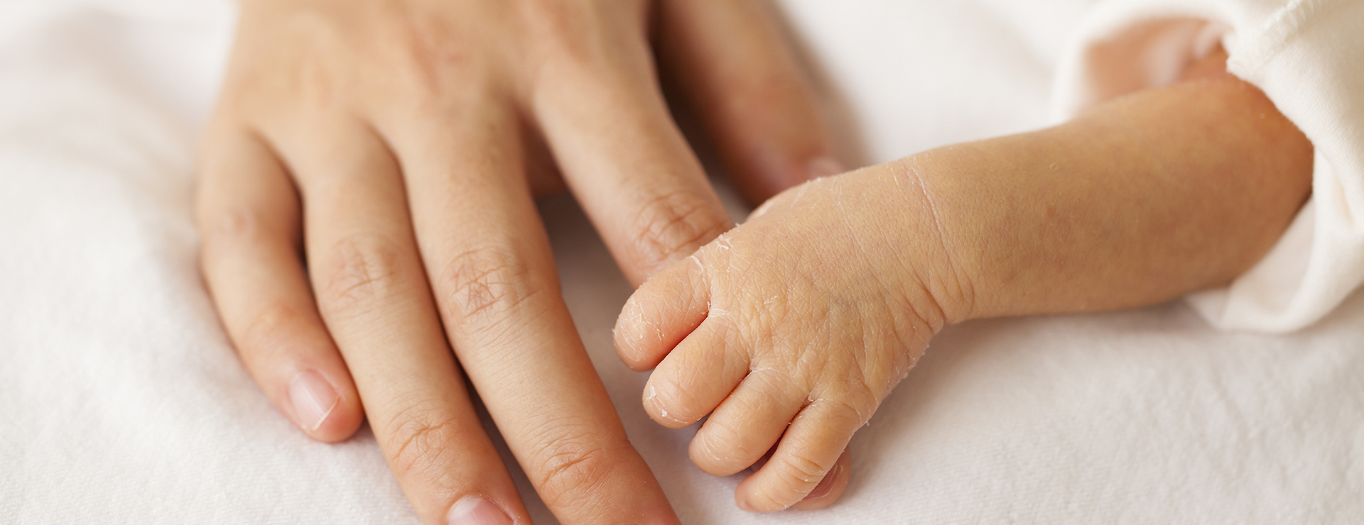 newborn holding mother's finger