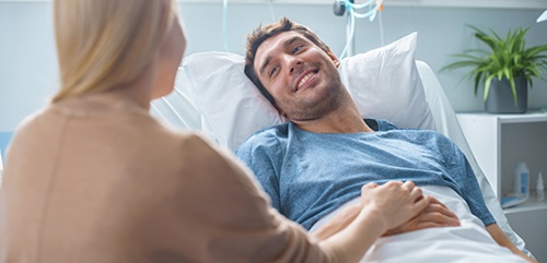 man in hospital bed smiling at woman