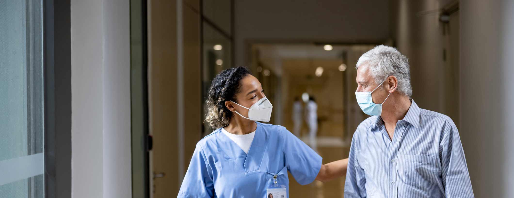 Masked man walks with masked doctor.
