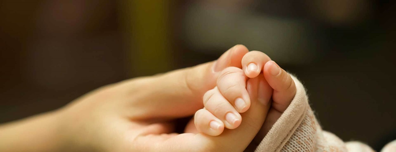 Baby holding mother's hand.