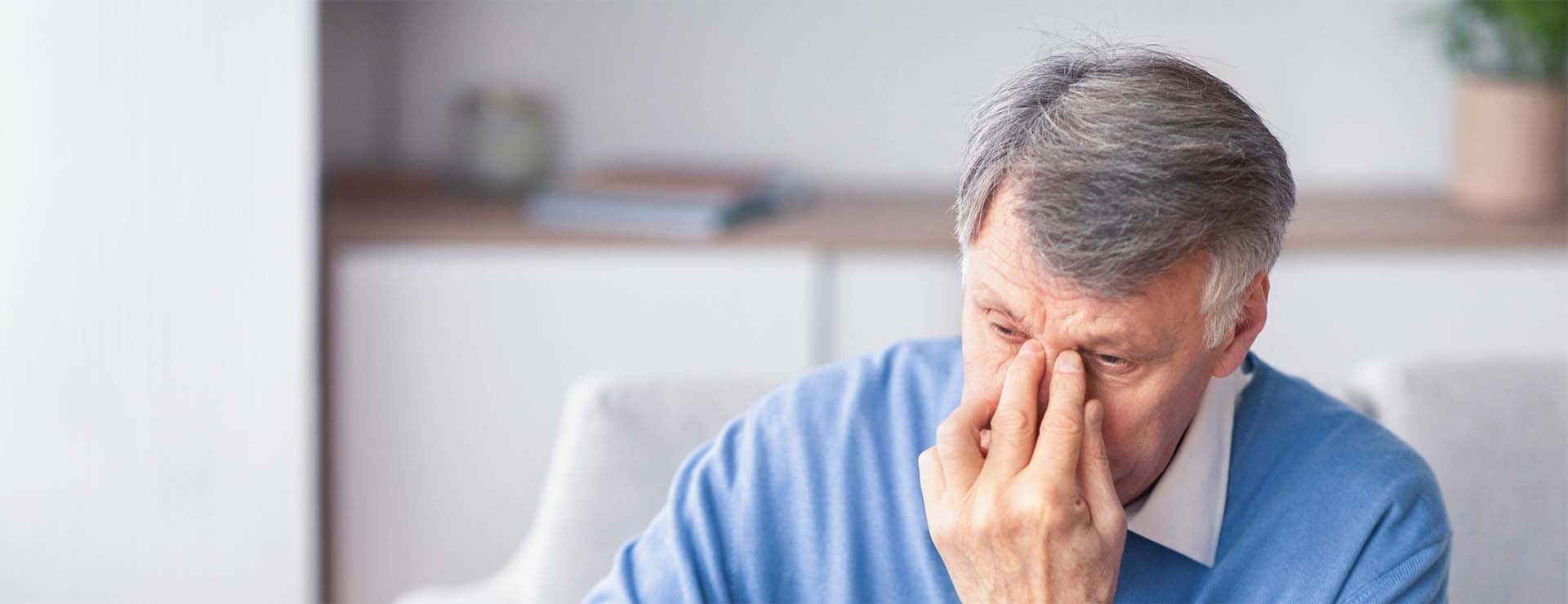 Man pinches the bridge of his nose due to eye pain