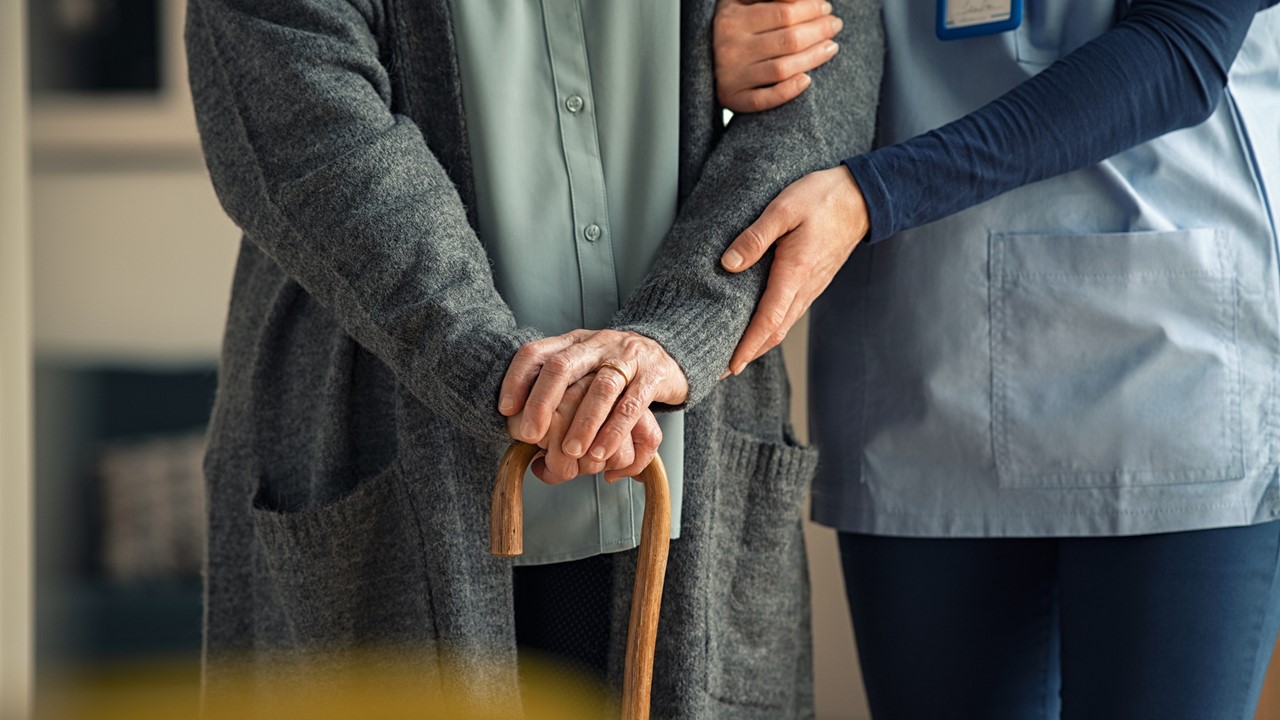 Aide helping senior woman walk
