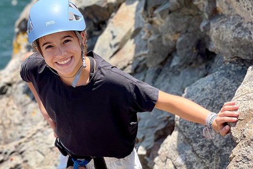 Adelaide smiling at the camera while rock climbing