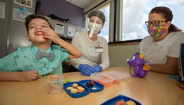 Gabriel works with Barbara Hancock, center, a speech-language pathologist at Johns Hopkins All Children's Hospital, as his mom Cherry looks on.