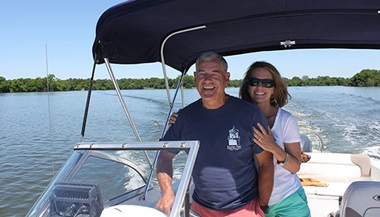 Jan operating his boat, his wife smiling over his shoulder.