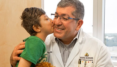 George Jallo, M.D. receives a kiss as thanks from Rafael for removing a tumor from the Brazilian boy's spinal cord.
