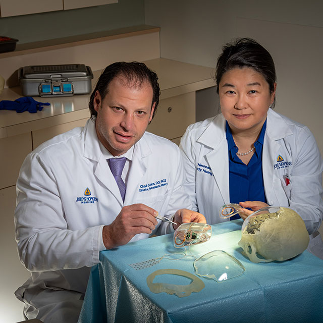 Two Johns Hopkins doctors work on rebuilding a skull.