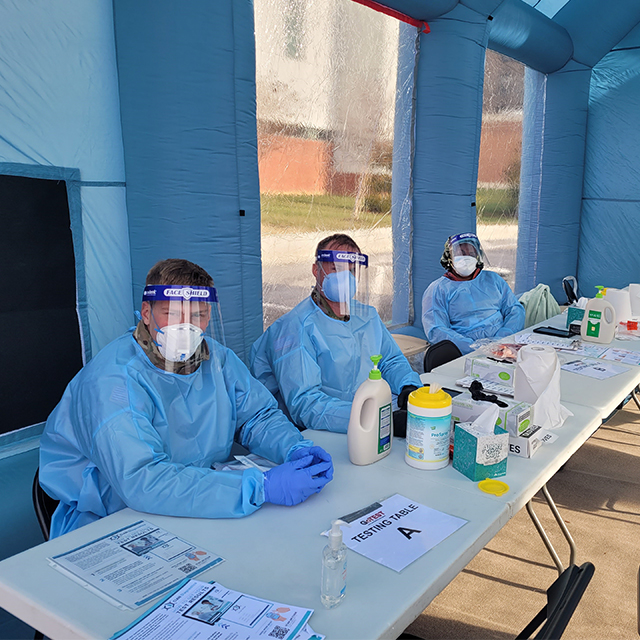 Photo of National Guard sitting at testing table in inflatable tent at Johns Hopkins Bayview.